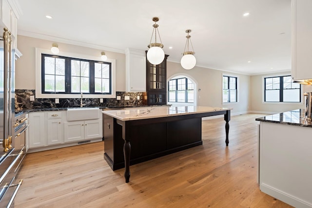 kitchen featuring dark stone countertops, a kitchen island, pendant lighting, and backsplash