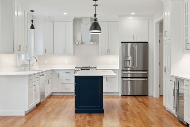 kitchen featuring sink, white cabinetry, stainless steel appliances, a kitchen island, and wall chimney exhaust hood