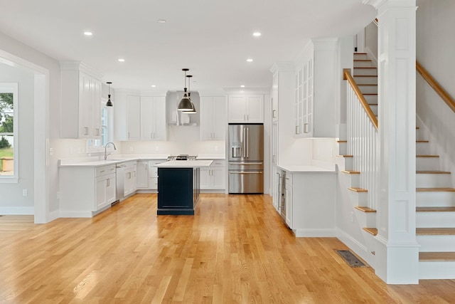 kitchen featuring pendant lighting, stainless steel appliances, white cabinets, and a kitchen island