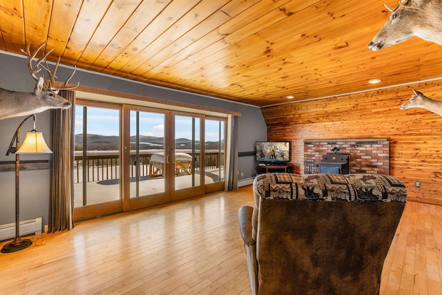 living room featuring wood walls, a wood stove, wooden ceiling, light wood-type flooring, and french doors