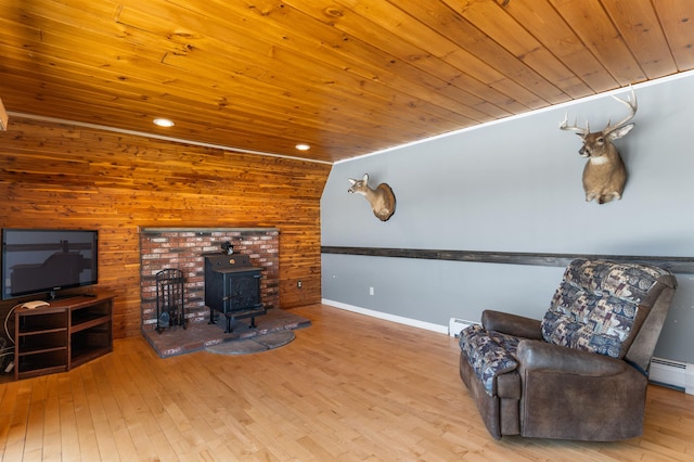 sitting room featuring a baseboard heating unit, a wood stove, wooden ceiling, and light hardwood / wood-style floors