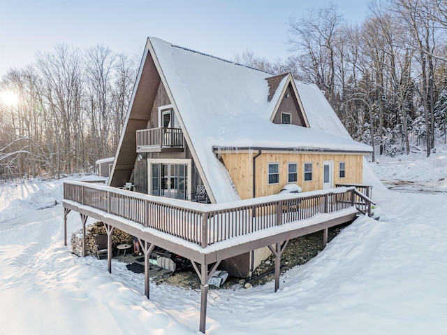 snow covered house featuring a wooden deck