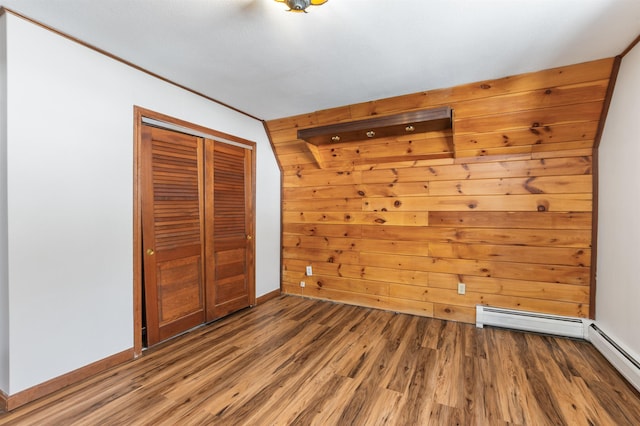 unfurnished bedroom featuring wood-type flooring, a baseboard heating unit, and a closet