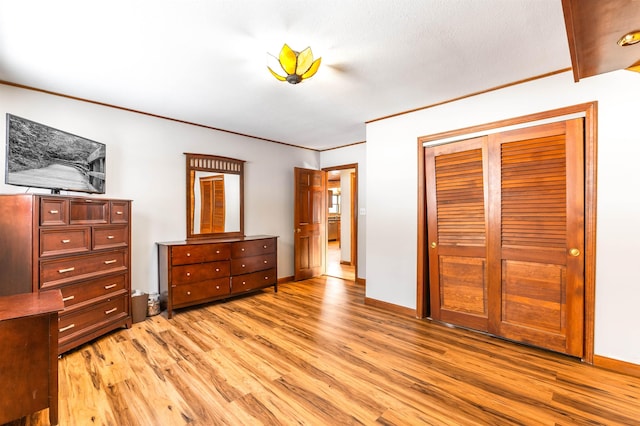 bedroom with ornamental molding, light hardwood / wood-style floors, and a closet