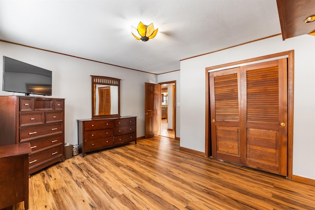 bedroom with light hardwood / wood-style flooring, ornamental molding, and a closet