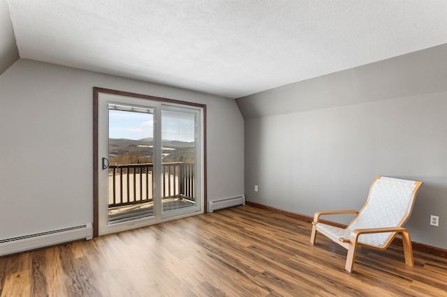 unfurnished room with wood-type flooring, vaulted ceiling, a baseboard heating unit, and a textured ceiling