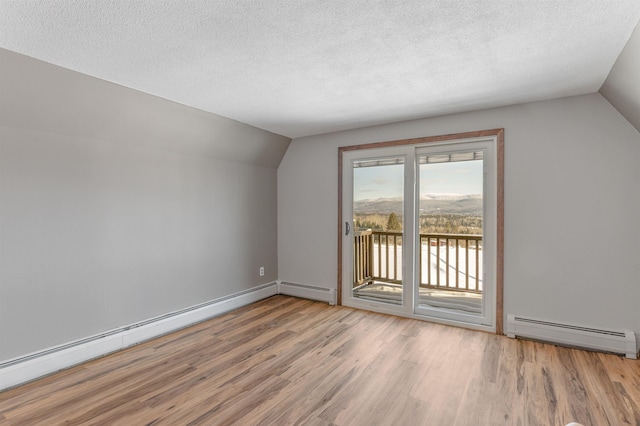 bonus room featuring a baseboard heating unit, vaulted ceiling, and light hardwood / wood-style floors