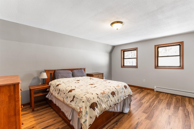 bedroom featuring a baseboard heating unit, light hardwood / wood-style flooring, a textured ceiling, and vaulted ceiling