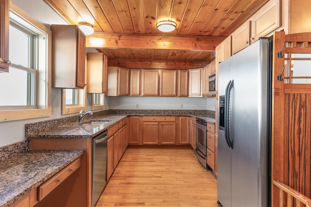 kitchen with appliances with stainless steel finishes, sink, dark stone counters, wood ceiling, and light hardwood / wood-style flooring