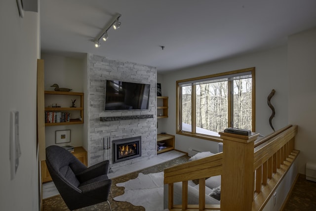 living room with a fireplace, track lighting, and baseboard heating