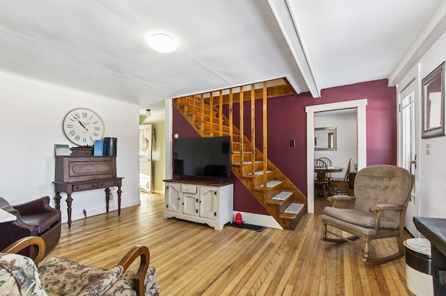 living room featuring beamed ceiling and light wood-type flooring