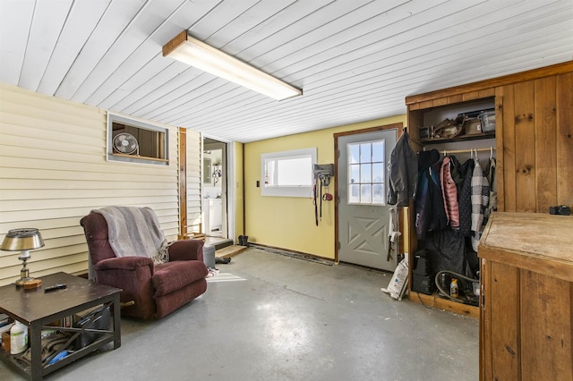 interior space with concrete floors, wooden ceiling, and wooden walls