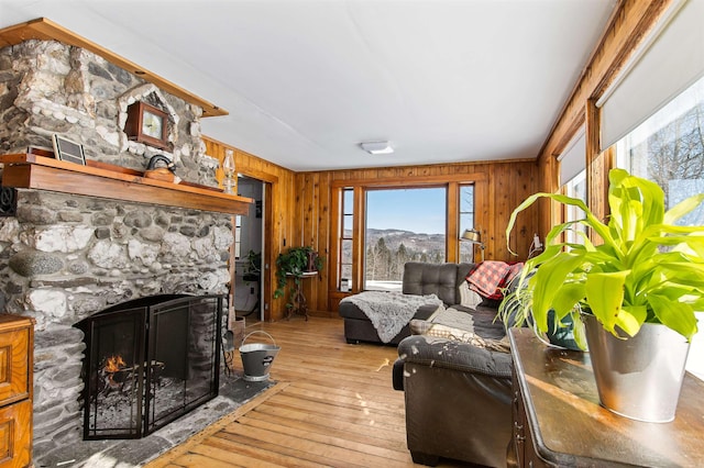 living room with a fireplace, a mountain view, light hardwood / wood-style floors, and wood walls