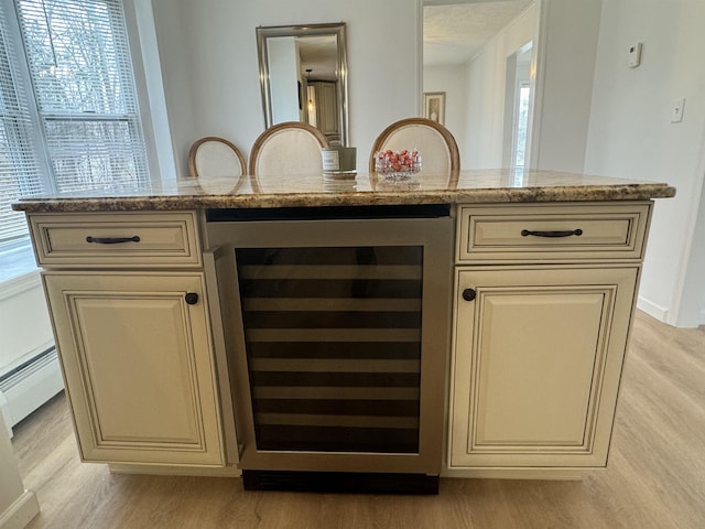 bar featuring wine cooler, cream cabinets, light stone counters, and light hardwood / wood-style floors