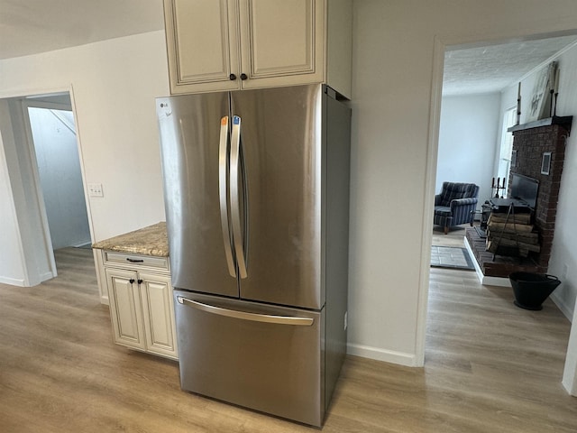 kitchen with light stone counters, stainless steel fridge, light hardwood / wood-style floors, and a textured ceiling