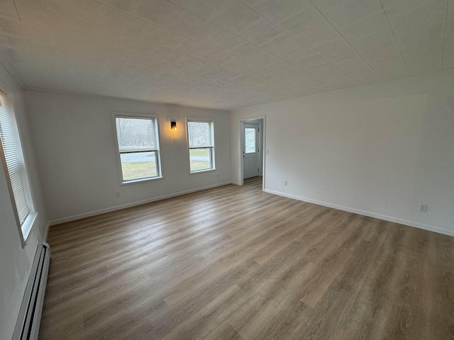 unfurnished room featuring light hardwood / wood-style flooring and a baseboard heating unit