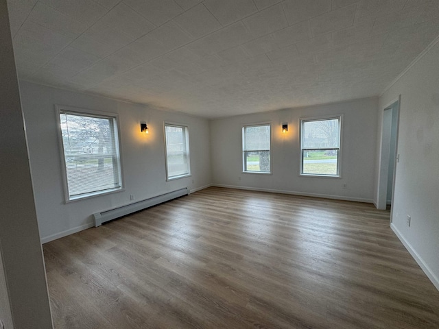 unfurnished room featuring a baseboard heating unit and light hardwood / wood-style flooring