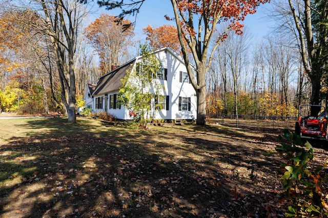 view of side of property featuring a shingled roof, fence, a lawn, and a gambrel roof