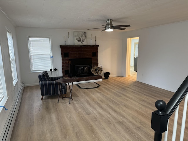 living room with ceiling fan, a brick fireplace, light hardwood / wood-style flooring, and a baseboard heating unit