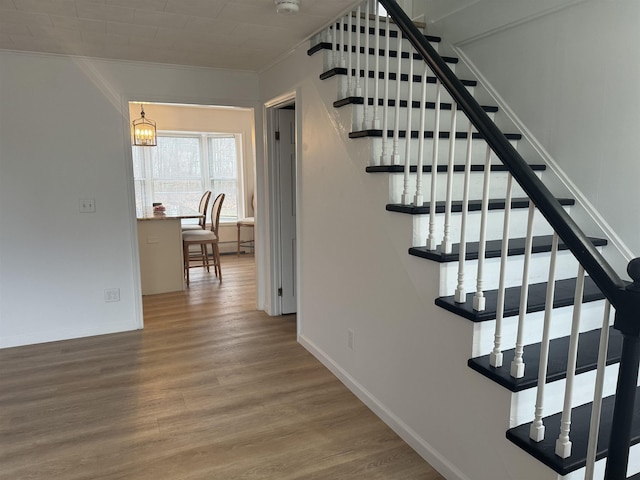 stairs with wood-type flooring and ornamental molding