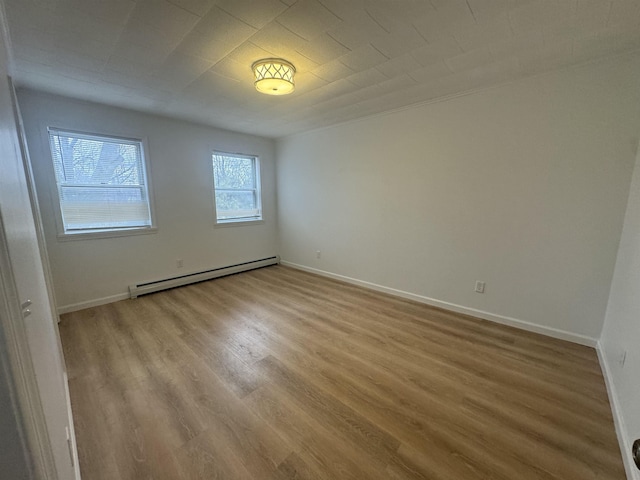 empty room featuring a baseboard heating unit and light hardwood / wood-style flooring