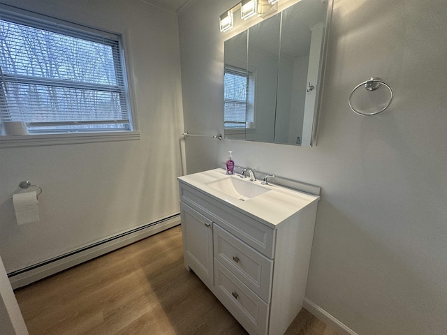 bathroom with vanity, hardwood / wood-style flooring, a baseboard radiator, and a wealth of natural light