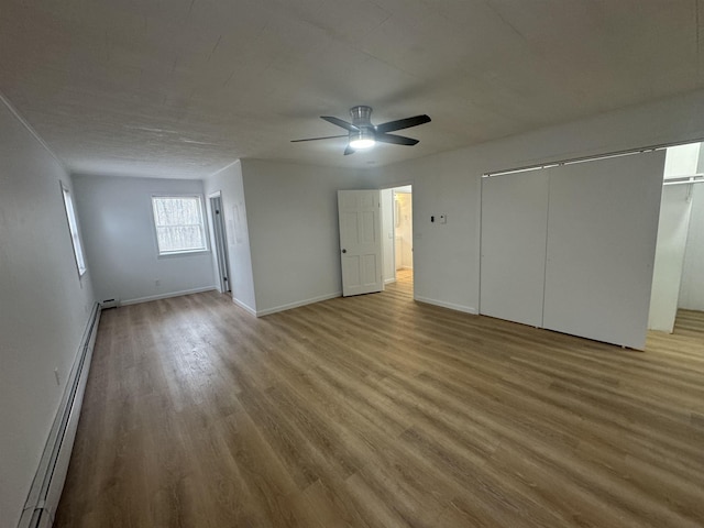 unfurnished bedroom featuring a baseboard radiator, a closet, ceiling fan, and light hardwood / wood-style flooring