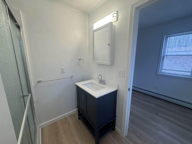 bathroom with ornamental molding, wood-type flooring, vanity, and a baseboard heating unit