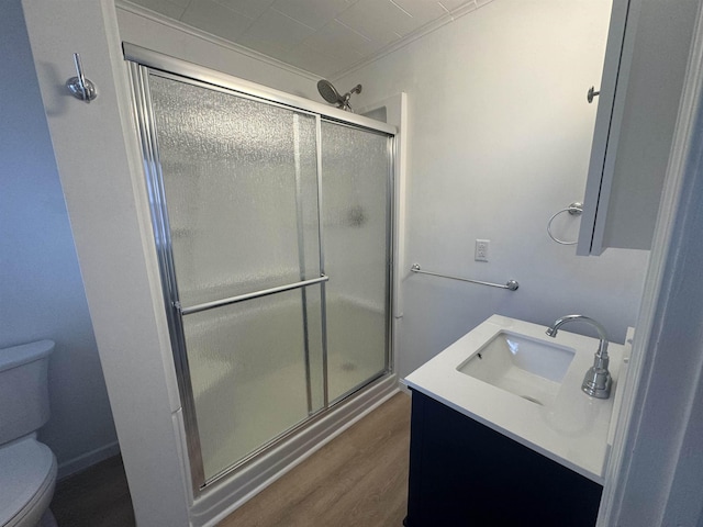 bathroom featuring vanity, a shower with shower door, wood-type flooring, and toilet