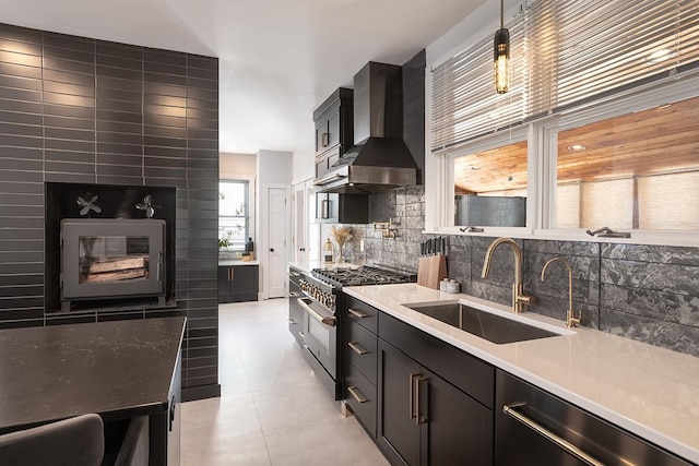 kitchen with wall chimney exhaust hood, sink, light tile patterned floors, high end stove, and decorative backsplash