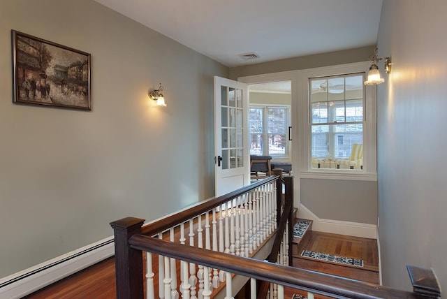 corridor with wood-type flooring and baseboard heating