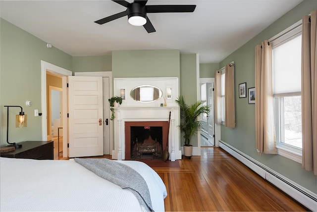 bedroom with a baseboard radiator, dark hardwood / wood-style floors, and ceiling fan