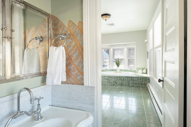 bathroom with tile patterned flooring, sink, a baseboard heating unit, and tiled bath