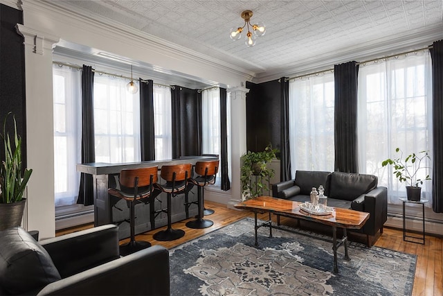 sitting room featuring crown molding, plenty of natural light, decorative columns, and a baseboard radiator