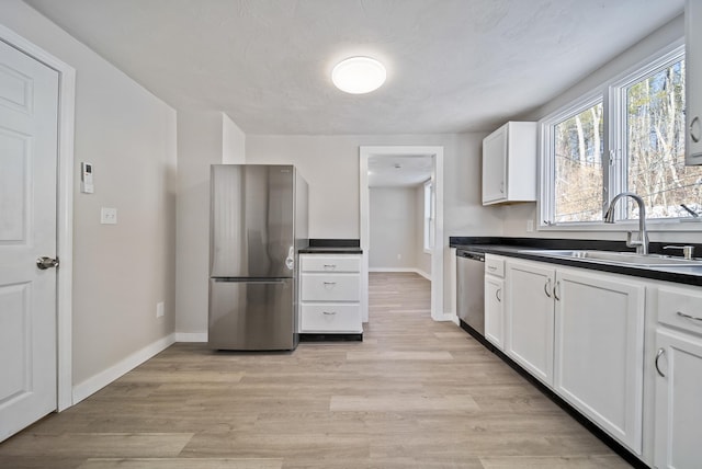 kitchen with white cabinetry, appliances with stainless steel finishes, sink, and light hardwood / wood-style floors