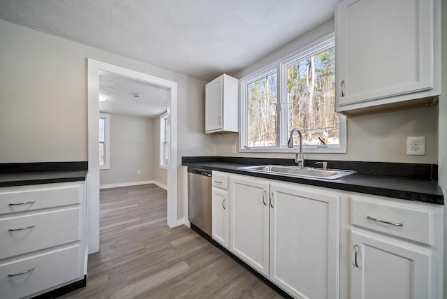 kitchen with white cabinetry, sink, stainless steel dishwasher, and light wood-type flooring