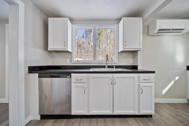 kitchen with stainless steel dishwasher, a wall mounted air conditioner, sink, and white cabinets