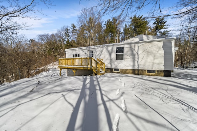 snow covered rear of property featuring a deck