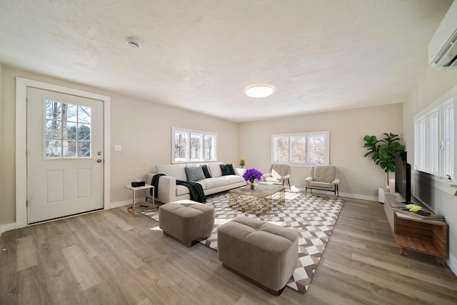 living room with a wall mounted air conditioner and light wood-type flooring