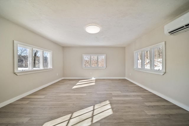 empty room featuring an AC wall unit and light hardwood / wood-style floors