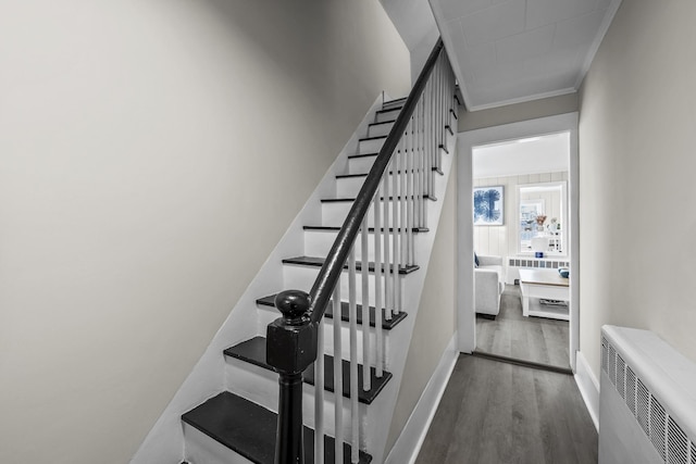 stairway with crown molding, radiator, and hardwood / wood-style floors