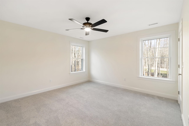 spare room featuring light carpet, ceiling fan, and a healthy amount of sunlight