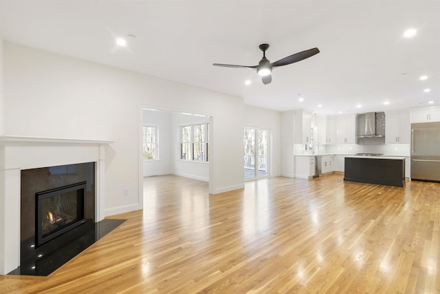 unfurnished living room featuring ceiling fan, sink, and light wood-type flooring