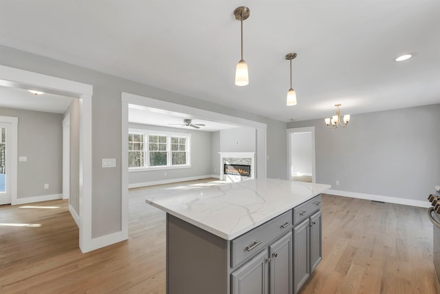 kitchen featuring light stone counters, decorative light fixtures, light hardwood / wood-style floors, and a kitchen island