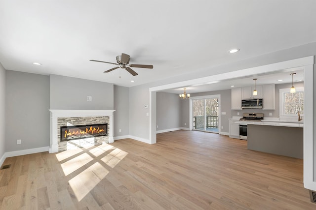 unfurnished living room featuring ceiling fan, a fireplace, and light wood-type flooring