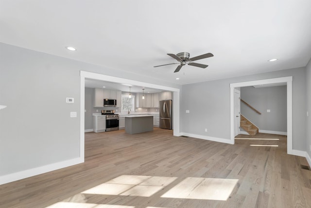 unfurnished living room featuring ceiling fan, sink, and light hardwood / wood-style floors