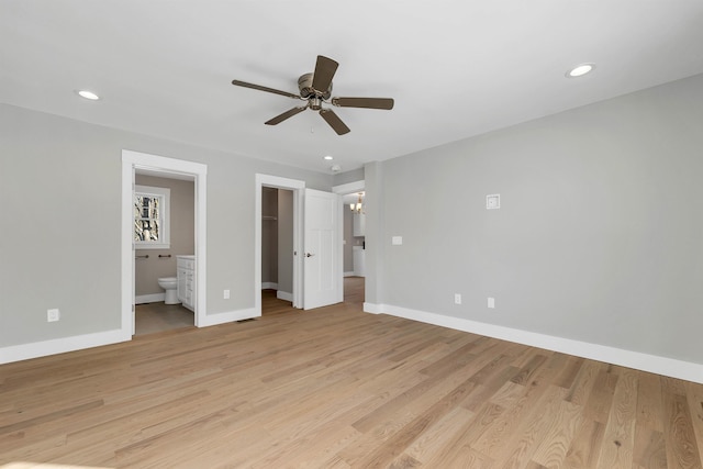 unfurnished bedroom featuring ensuite bathroom, a spacious closet, light hardwood / wood-style floors, a closet, and ceiling fan with notable chandelier