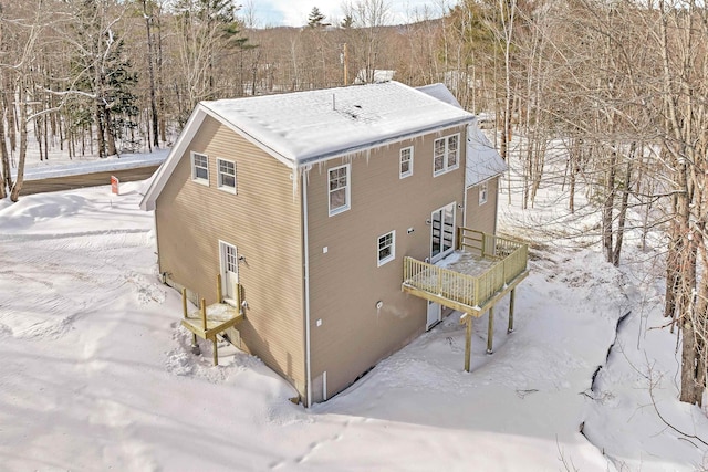 snow covered back of property with a wooden deck