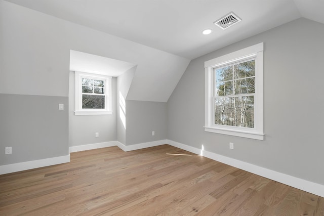 bonus room featuring lofted ceiling, plenty of natural light, and light wood-type flooring