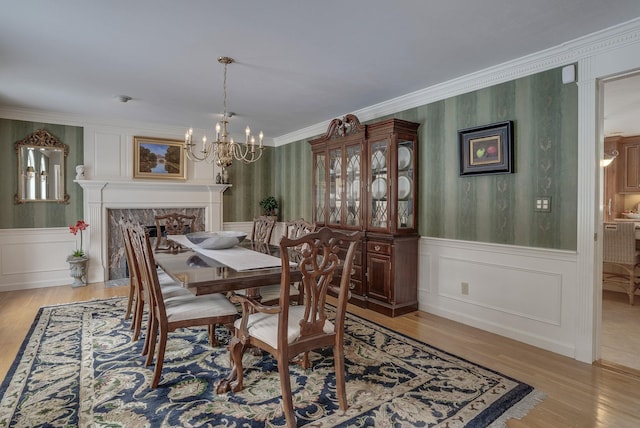 dining room with ornamental molding, light hardwood / wood-style floors, and a notable chandelier